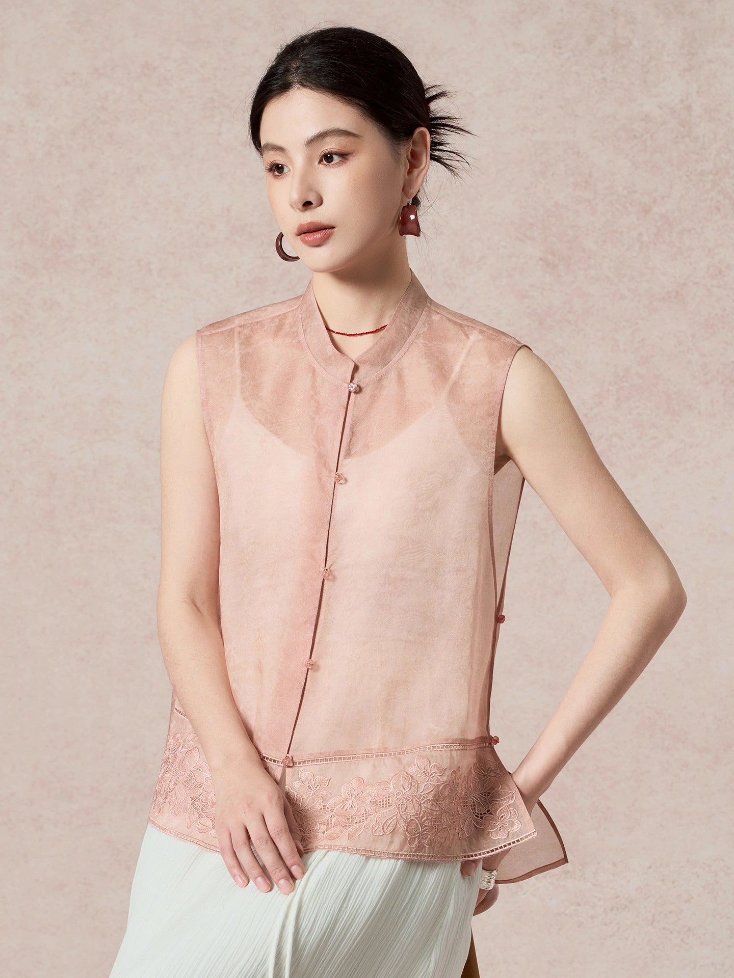 Side view of a pink silk vest featuring a relaxed fit, sheer fabric, and intricate embroidery details at the hem.