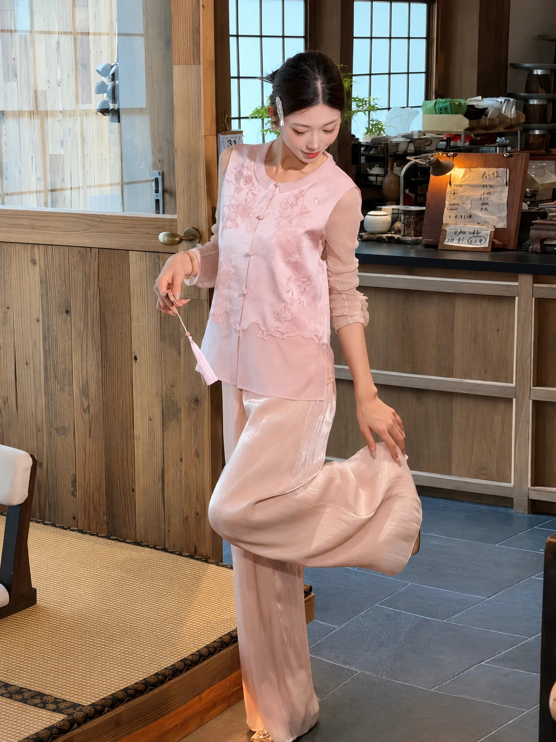 Side view of a pink wide-leg pants and embroidered top set, styled with a tassel fan, showcasing the flowy silhouette.