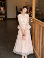 Model wearing a pink tulle maxi skirt with lace details and a ruffled hem, holding a pink handbag, styled with a floral embroidery vest, crafted from 100% polyester.