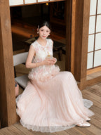 Sitting model in a pink tulle and lace maxi skirt, holding a small bag, highlighting the delicate details and comfortable fit of the 100% polyester fabric.