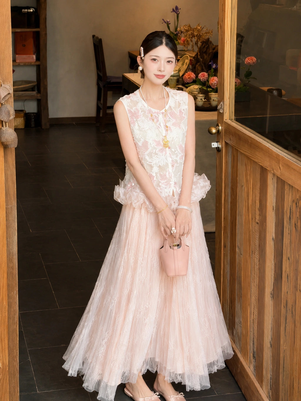 Full body shot of a pink pleated tulle skirt with lace overlay, styled with a white embroidered top and pink handbag, perfect for a romantic New Chinese look.