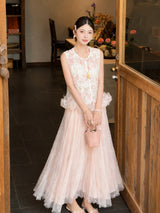 Full body shot of a pink pleated tulle skirt with lace overlay, styled with a white embroidered top and pink handbag, perfect for a romantic New Chinese look.