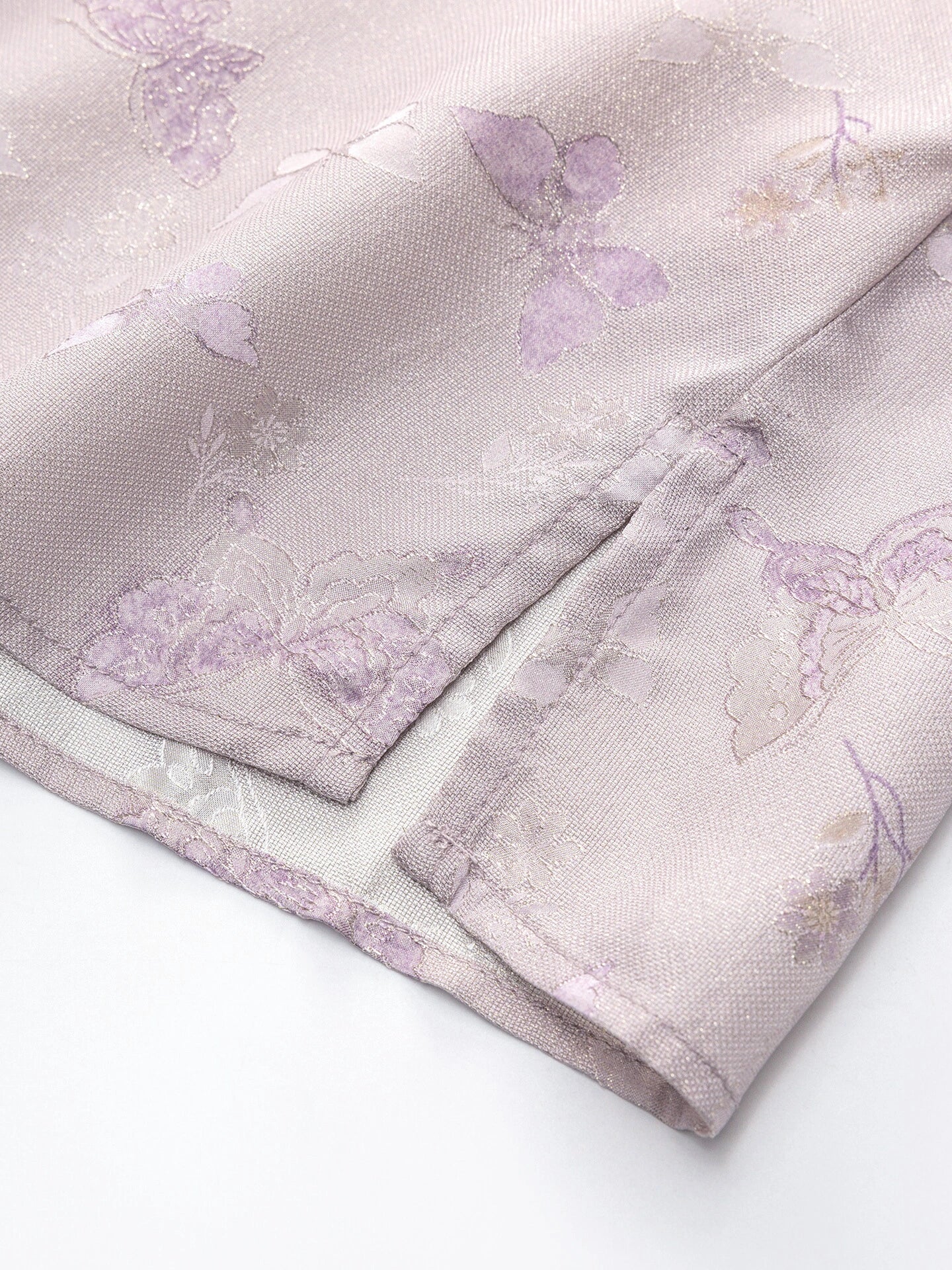 Close-up of a light purple 23 momme silk fabric featuring delicate butterfly jacquard patterns and subtle floral details, 94% mulberry silk blend.