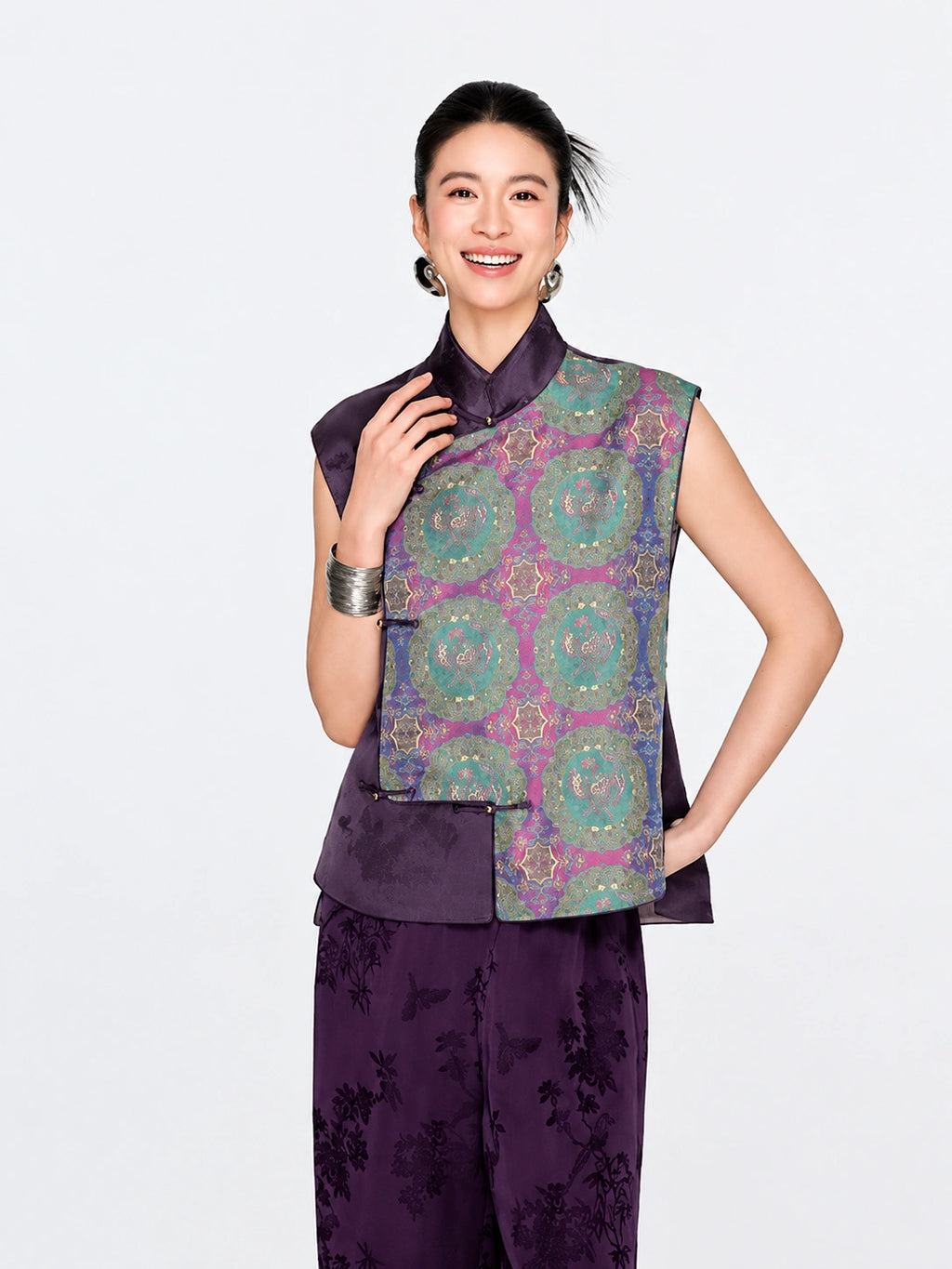 Front view of a woman wearing the purple mulberry silk vest with turquoise, blue and gold Shu brocade medallions.