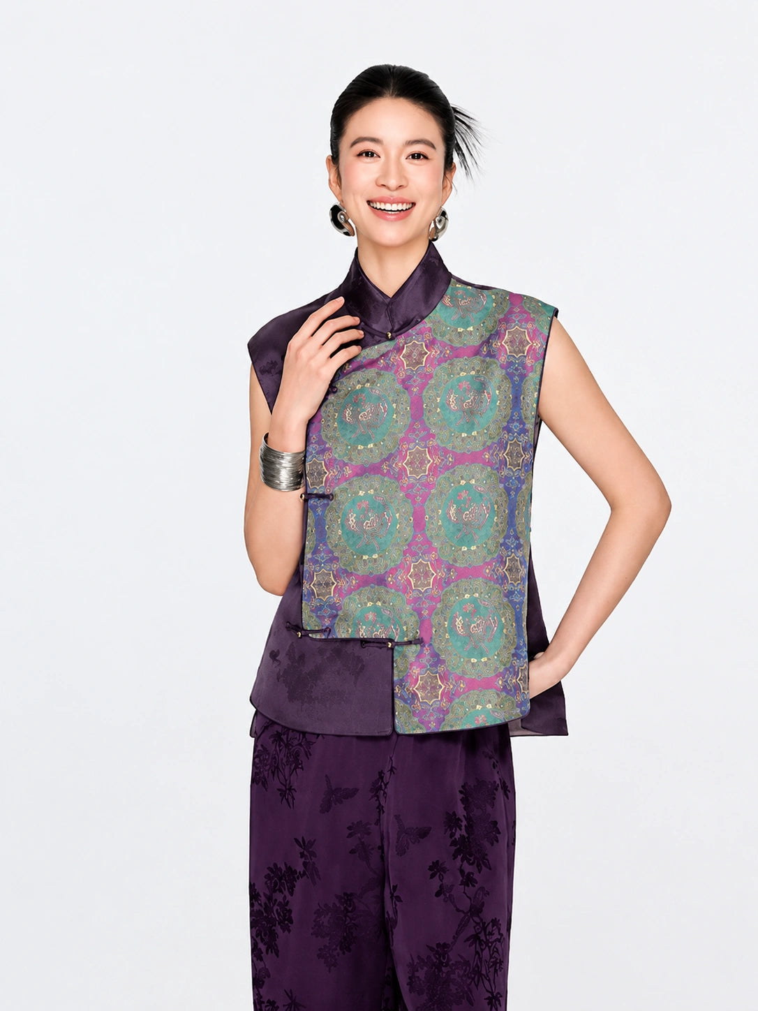 Front view of a woman wearing the purple mulberry silk vest with turquoise, blue and gold Shu brocade medallions.