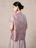 Back view of a purple silk Cheongsam top showcasing the intricate floral jacquard pattern and relaxed silhouette, paired with a pleated skirt.