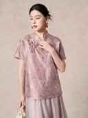 Front view of a women's purple silk top with a stand collar, short sleeves, and intricate jacquard pattern, styled with a matching pleated skirt.