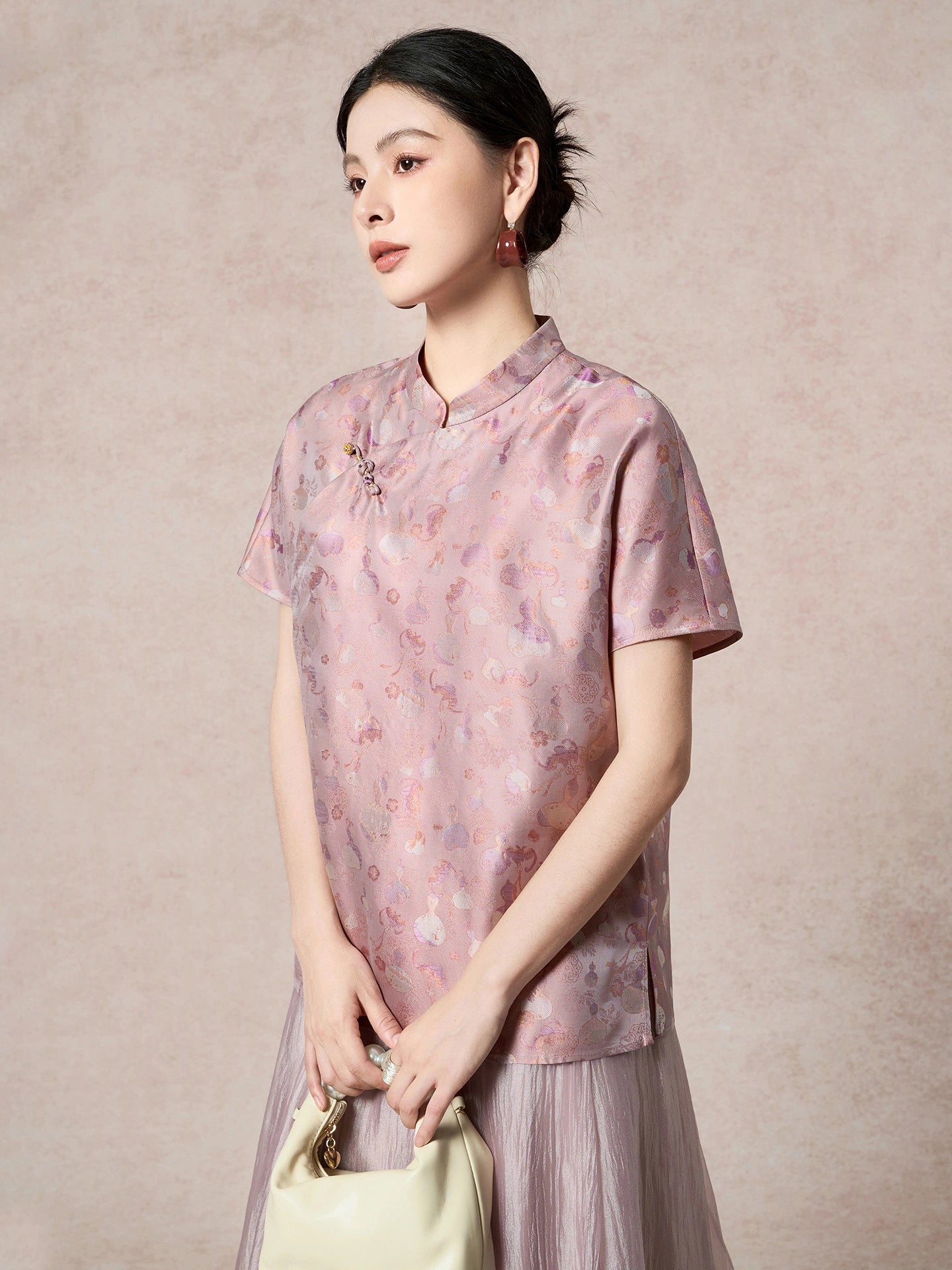 Model wearing a purple silk Cheongsam top with a relaxed fit, holding a cream handbag, showcasing the elegant drape and lustrous sheen.