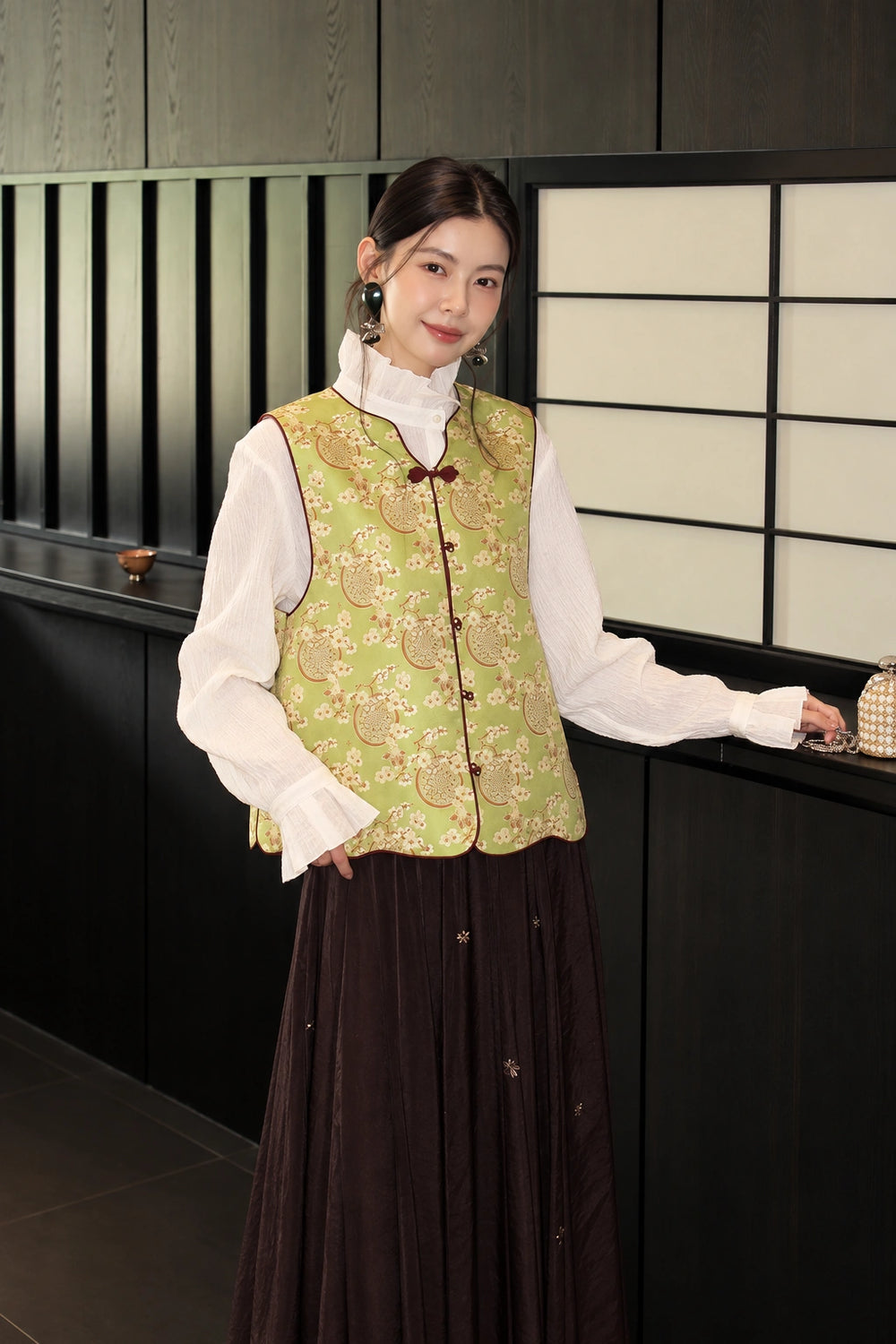 Front view of the green floral silk vest with a V-neck and burgundy button trim