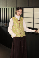 Front view of the green floral silk vest with a V-neck and burgundy button trim