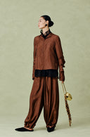 Full-length styling view of the red-brown shirt paired with matching trousers and a gold handbag.