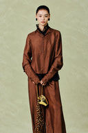 Model wearing the red-brown button-detail shirt with a black inner layer and matching trousers.