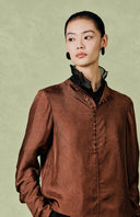 Upper-body view highlighting the shirt’s neckline, covered buttons and red-brown fabric.