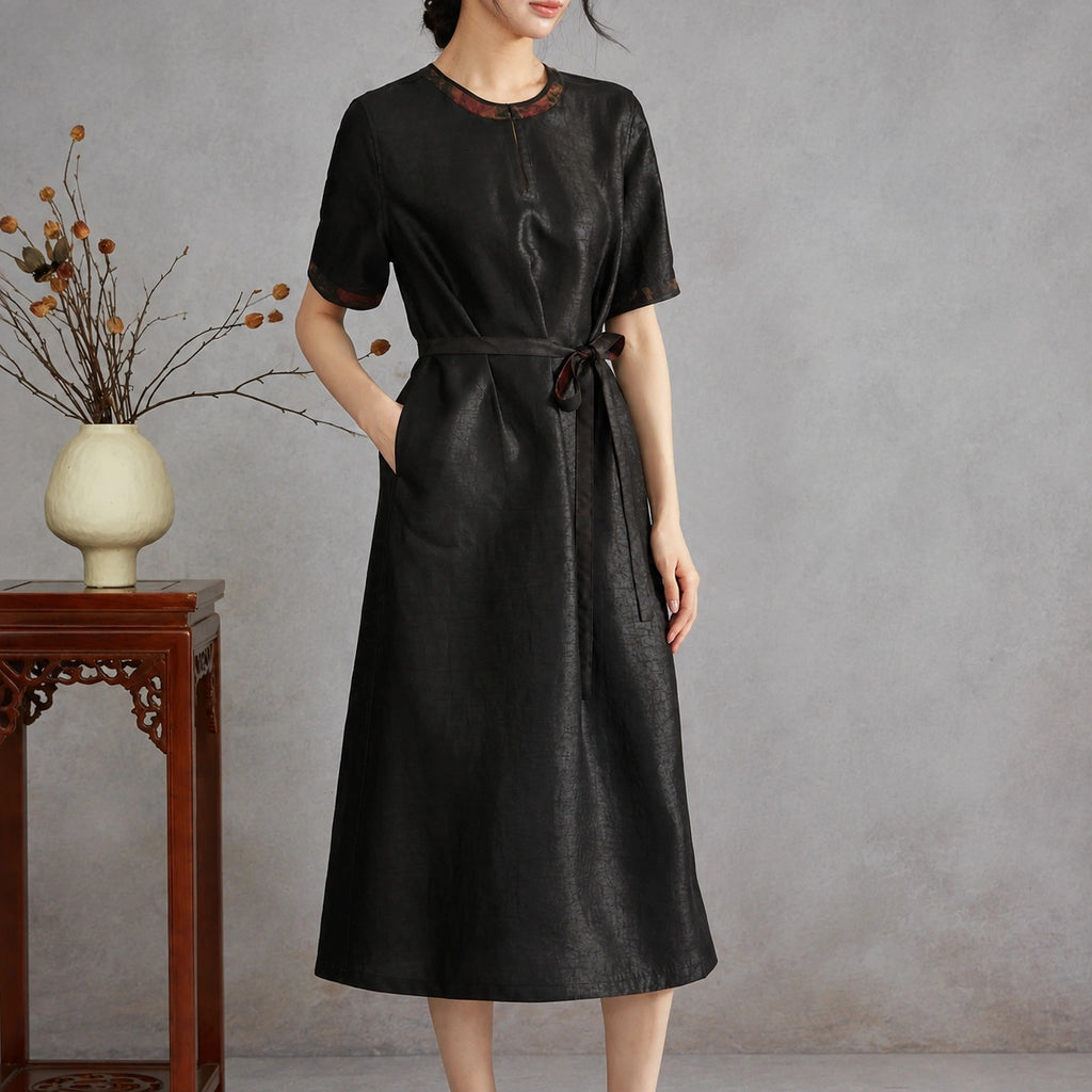 Woman wearing the black crackle side of a reversible Xiangyunsha silk midi dress with a tie waist