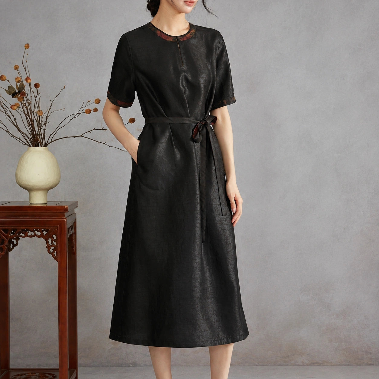 Woman wearing the black crackle side of a reversible Xiangyunsha silk midi dress with a tie waist