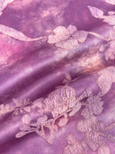 Draped purple fabric highlighting the jacquard texture and pink floral motifs.