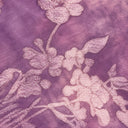 Macro view of the raised pink floral pattern on purple jacquard fabric.