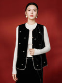 Model wearing the black side of the reversible vest open over a cream knit