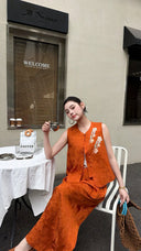 Sitting woman in a terracotta orange Cheongsam vest set, holding a coffee cup, showcasing the vintage embroidery and relaxed fit.