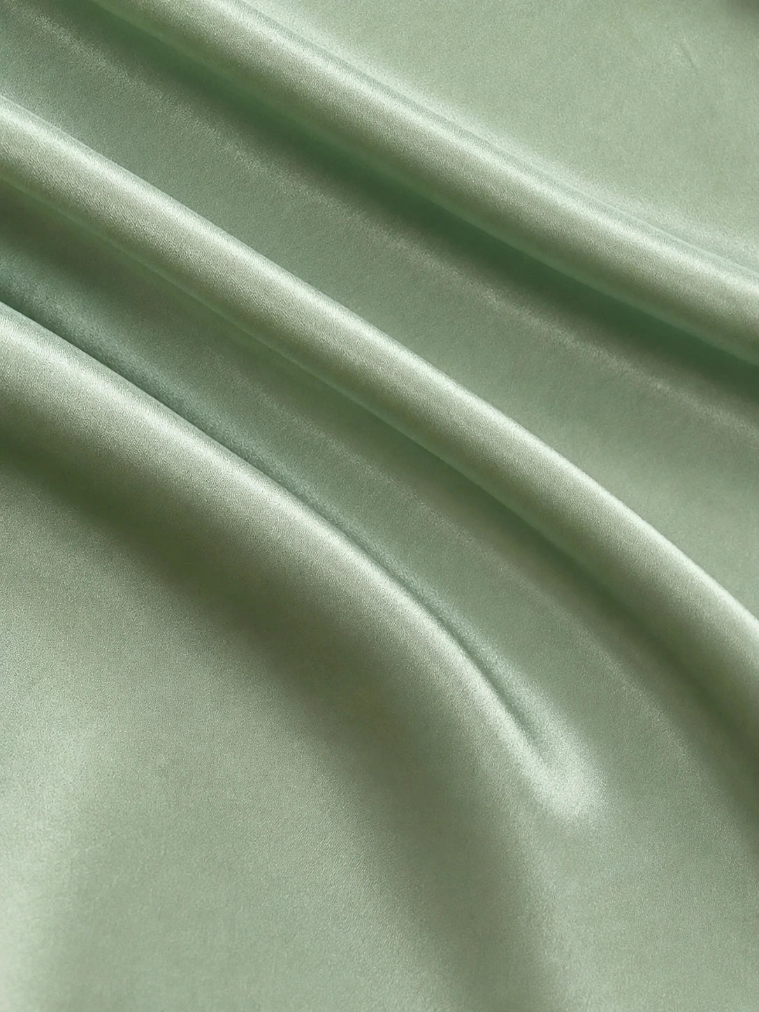 Close-up of the smooth sage green acetate and mulberry silk blend fabric