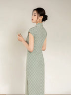 Back angled view of the sage green cheongsam dress with geometric jacquard pattern.