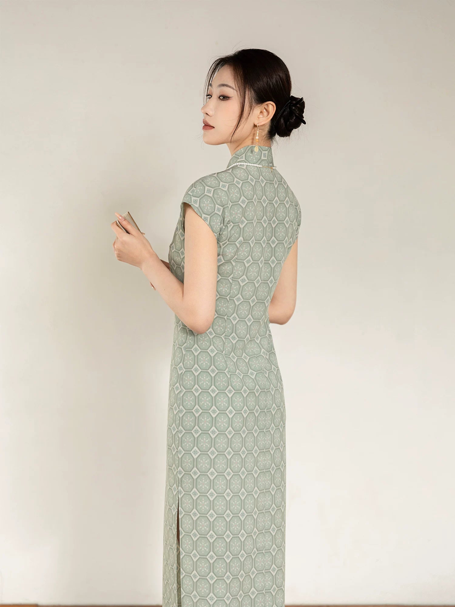 Back angled view of the sage green cheongsam dress with geometric jacquard pattern.