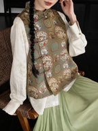 Close-up of the sage green silk vest showing its dragon and phoenix pattern, stand collar, and traditional frog closures.
