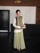 Model wearing a sage green Songjin silk Chinese vest with dragon and phoenix motifs over a white blouse.