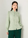 Detailed view of the floral jacquard texture on a sage green blouse.