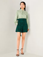 Sage green jacquard blouse with a stand collar and long sleeves.