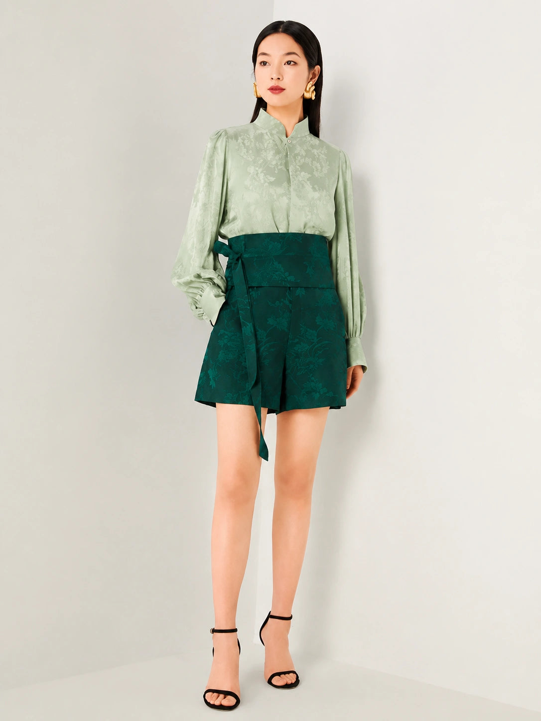 Sage green jacquard blouse with a stand collar and long sleeves.