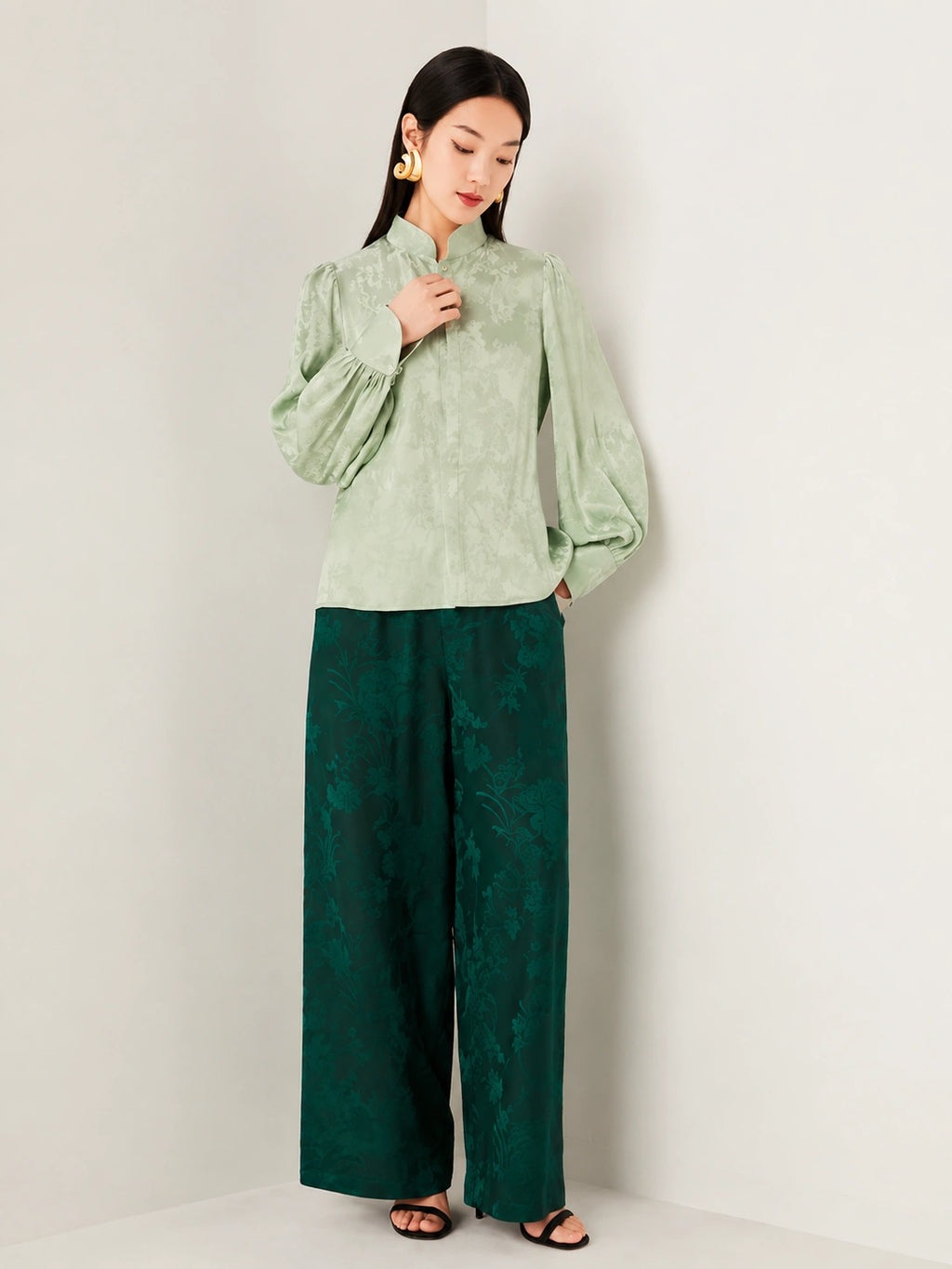 Model wearing a sage green jacquard blouse paired with wide-leg trousers.