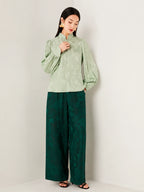 Model wearing a sage green jacquard blouse paired with wide-leg trousers.