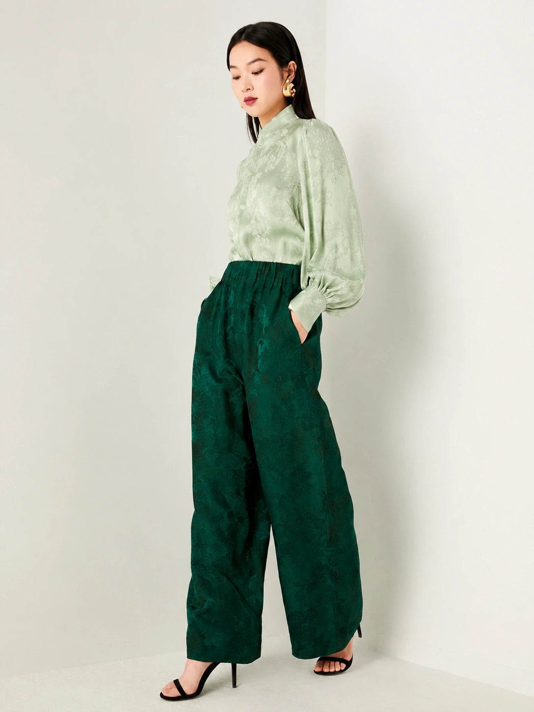 Side view of a lightweight sage green jacquard blouse.