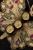 Macro view of the gold butterfly weaving, magenta accents and ornamental medallion buttons