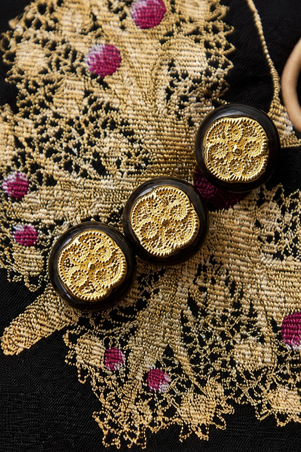 Macro view of the gold butterfly weaving, magenta accents and ornamental medallion buttons