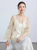 Model wearing a sheer cream/beige New Chinese style cardigan with floral embroidery and pearl trim, layered over a white slip dress, showcasing a delicate and elegant look.