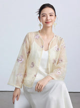 Model wearing a sheer cream/beige New Chinese style cardigan with floral embroidery and pearl trim, layered over a white slip dress, showcasing a delicate and elegant look.