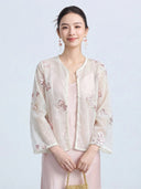 Front view of a women's sheer long-sleeve cover-up featuring delicate pink and purple floral embroidery with scalloped pearl trim.
