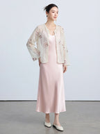 Full-body shot of a light beige sheer cardigan with pearl-trimmed edges and intricate embroidery, styled with a pink satin slip dress.