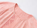 Close-up of the round neckline, button detail and embroidered front panel.