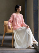 Seated side view showing the blouse’s pink jacquard pattern and embroidered front panel.