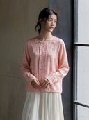Model wearing the pink embroidered jacquard blouse with a white skirt beside a window.