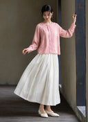 Full-length view of the pink long-sleeve blouse styled with a flowing white skirt.