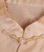 Close-up of the Mandarin collar, handmade frog button and butterfly jacquard pattern on blush pink silk