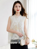 Model wearing a white sleeveless 100% silk vest with a stand collar and sheer cutwork butterfly patterns, paired with a black skirt and holding a pleated bag.