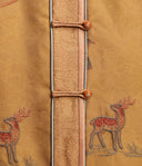 Close-up of embroidered deer and decorative buttons on textured antique gold silk