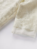 Close-up of the intricate floral embroidery on a sheer silk organza cardigan, showcasing the fine craftsmanship, subtle sheen, and premium texture.