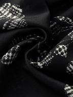 Close-up of the 100% silk crepe fabric showing the crisp white abstract floral print on a black background, highlighting the texture and sheen.