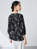 Back view of a black and white printed silk shirt with a relaxed fit, paired with white trousers, highlighting the elegant drape of the 100% silk fabric.